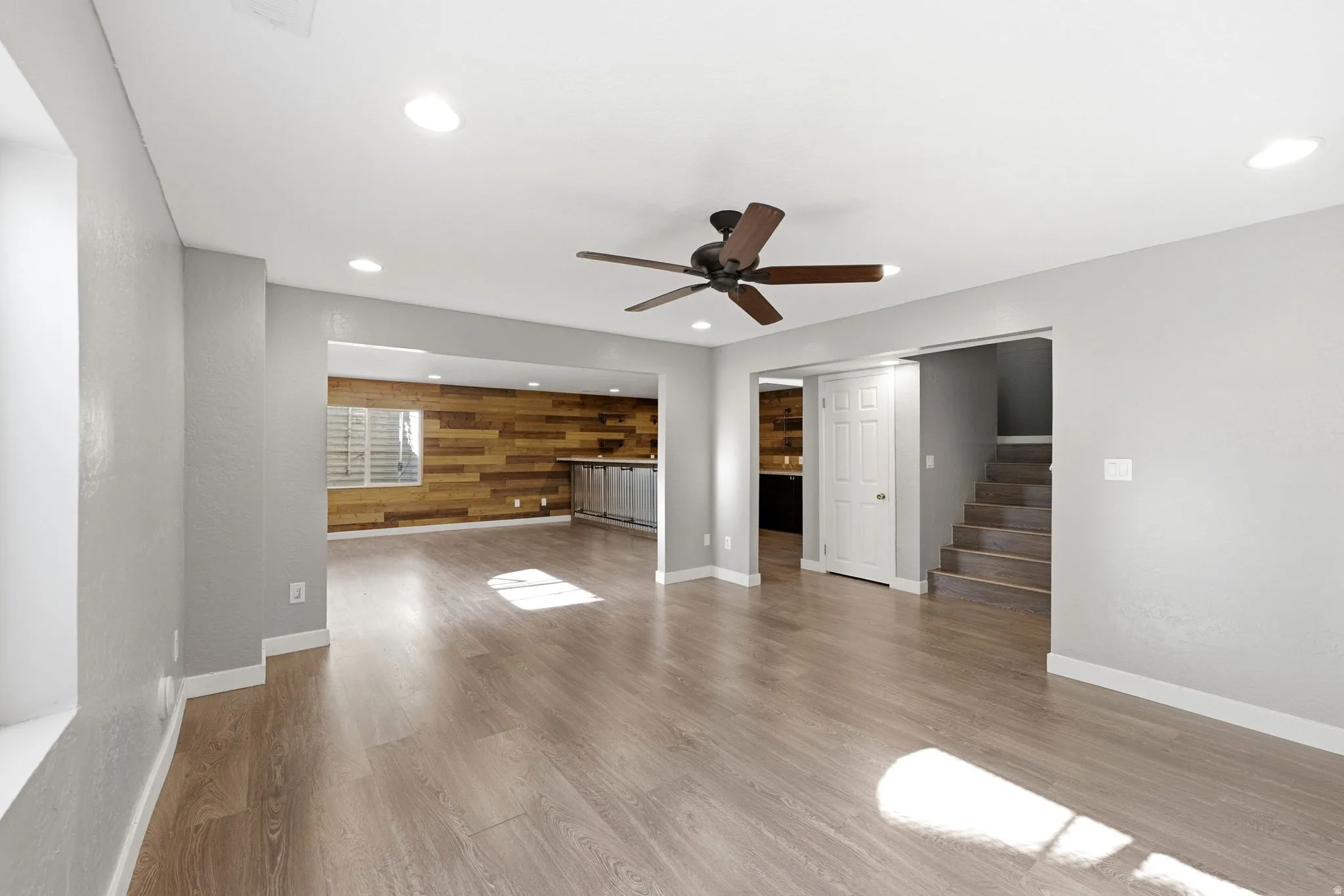 Spacious room featuring wood-finish flooring, recessed lighting, and a ceiling fan
