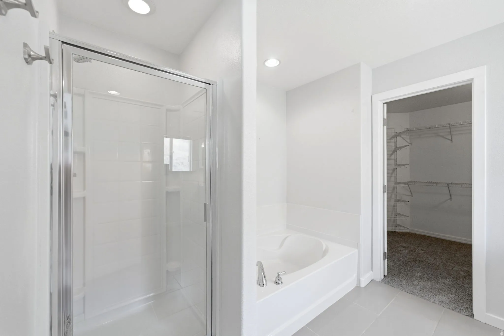 Bathroom featuring a glass-enclosed shower, a built-in soaking tub with chrome fixtures, recessed lighting, and light-toned floor tile