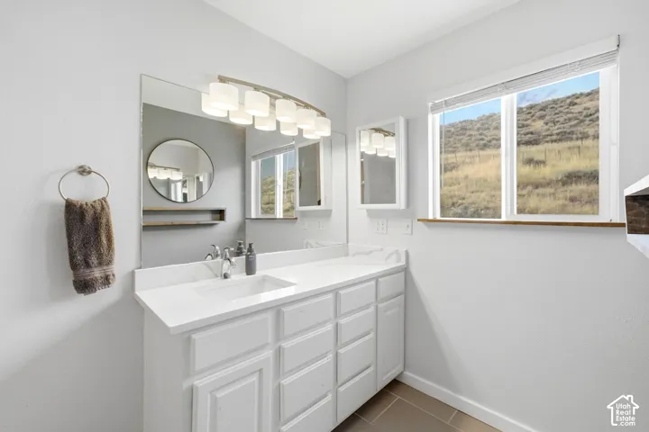 White vanity with a single basin, undermount sink, and a countertop featuring a subtle veining pattern
