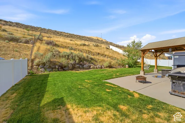 Expansive backyard featuring a lush lawn, concrete patio, and a covered pergola