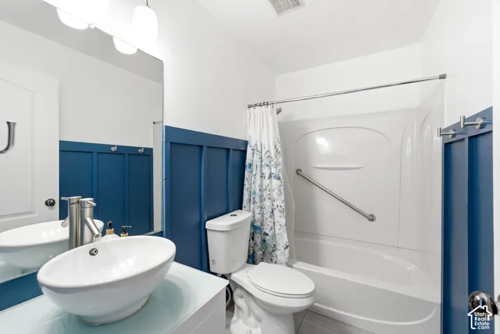 Bathroom featuring a vessel sink with a brushed nickel faucet, a full vanity mirror, and modern overhead lighting