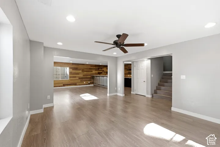 Spacious room featuring wood-finish flooring, recessed lighting, and a ceiling fan