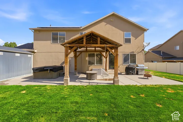 Expansive backyard featuring a manicured lawn, a large concrete patio, and a dedicated wooden gazebo structure