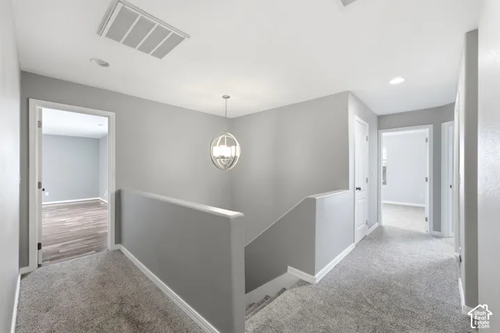 Upper-level landing featuring light gray carpeting and walls, a modern spherical pendant light, and white trim