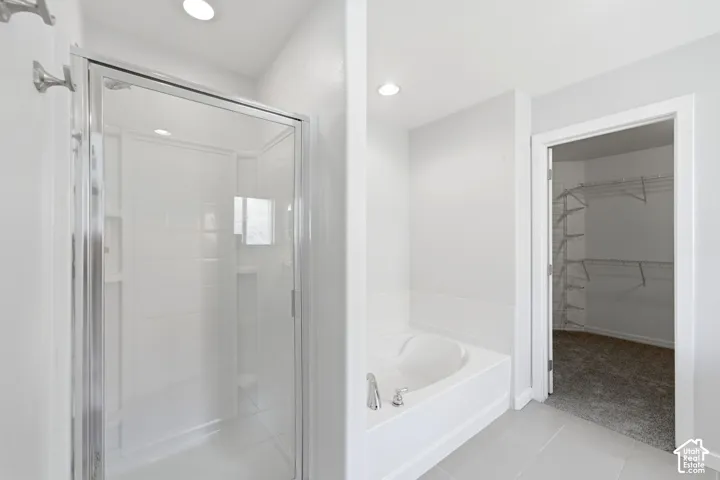 Bathroom featuring a glass-enclosed shower, a built-in soaking tub with chrome fixtures, recessed lighting, and light-toned floor tile