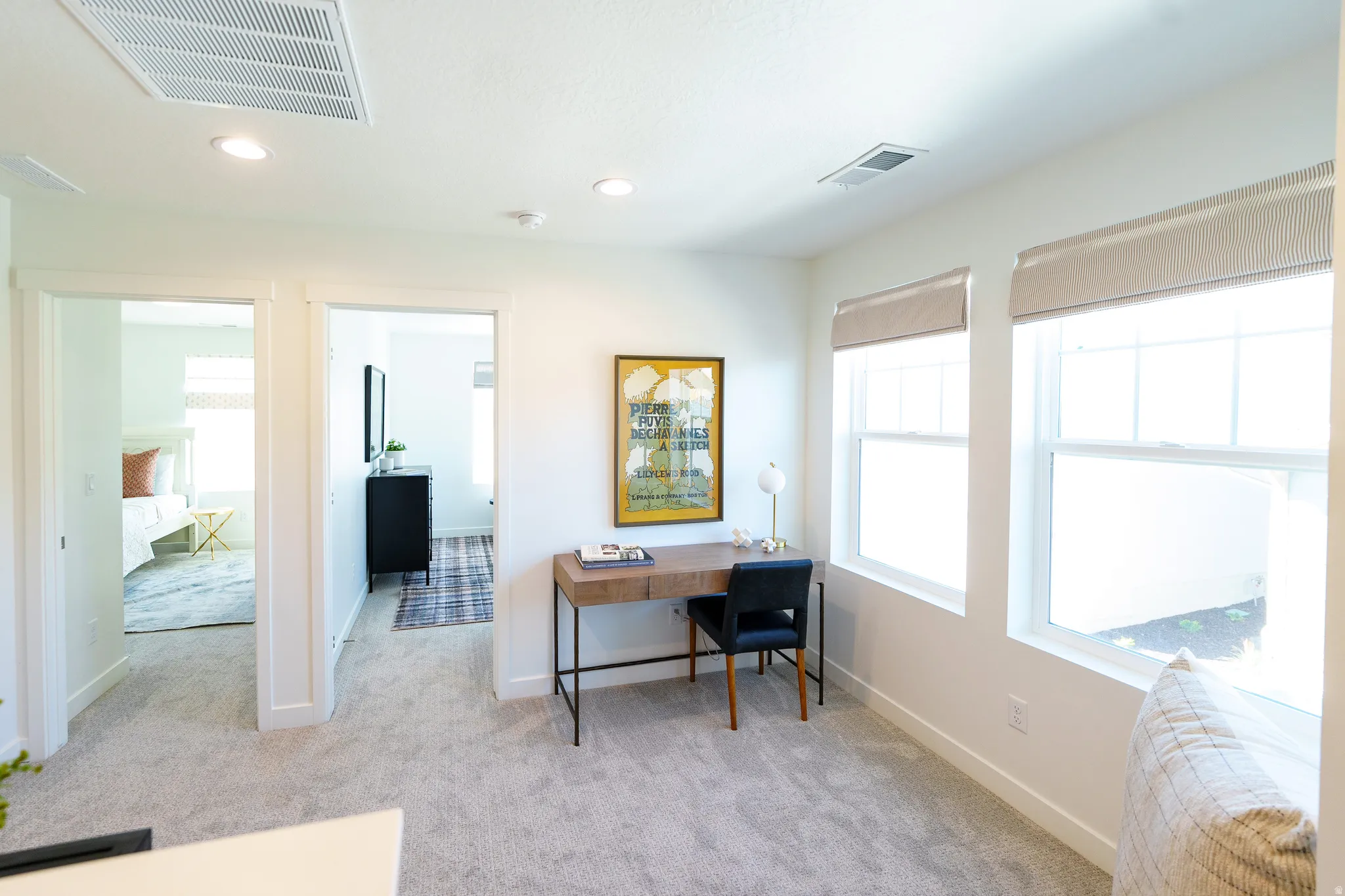 Carpeted multi-room area featuring recessed lighting, a built-in window seat, and two double-hung windows with neutral roller shades
