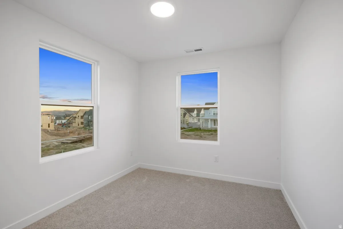 Carpeted room featuring two white-framed windows, white walls, and a ceiling-mounted light fixture