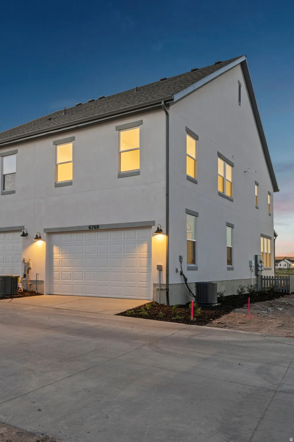 Contemporary multi-story residence featuring a white stucco exterior and a gray shingle roof