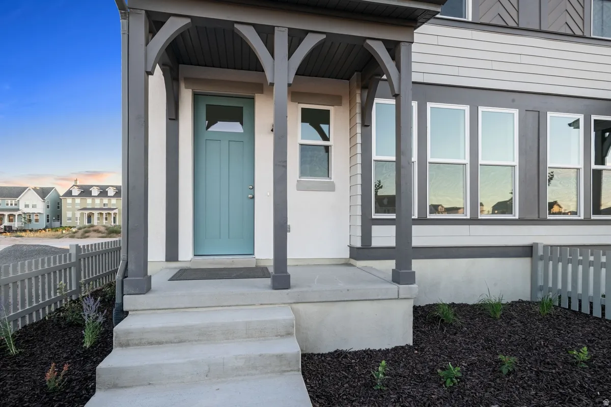 Inviting front entry featuring a teal-colored door with upper window pane, substantial concrete steps, and a covered porch with dark-toned architectural supports