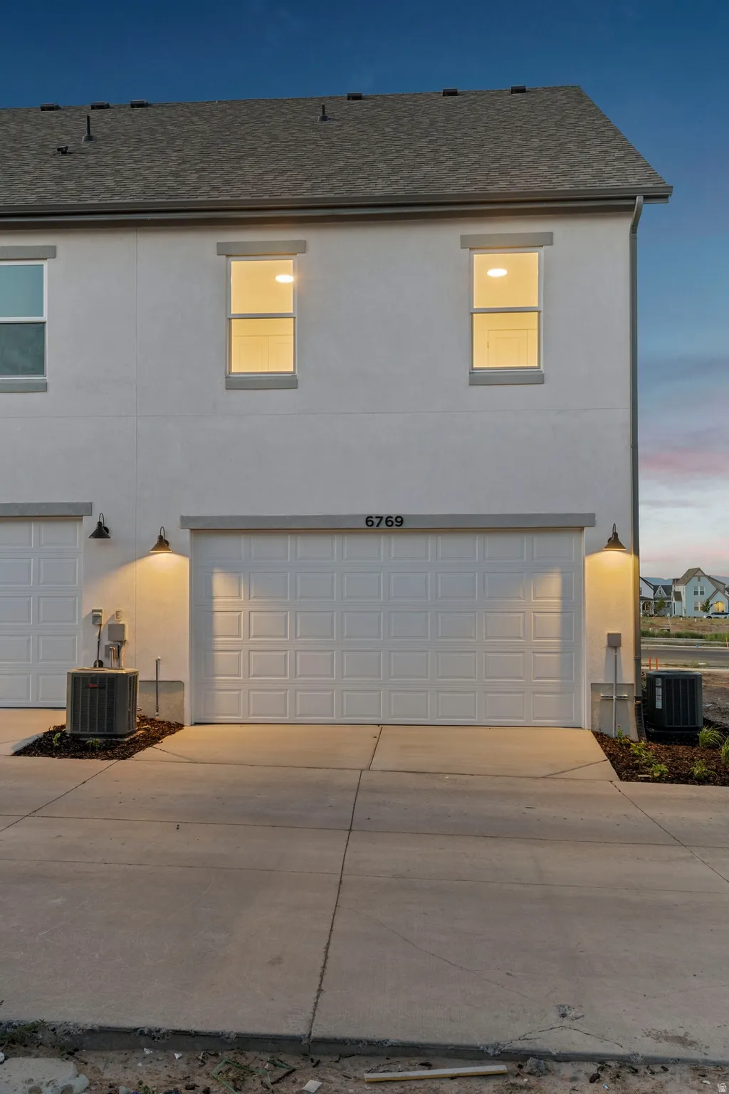 Contemporary facade featuring a two-car garage with paneling, stucco exterior, and a grey shingle roof