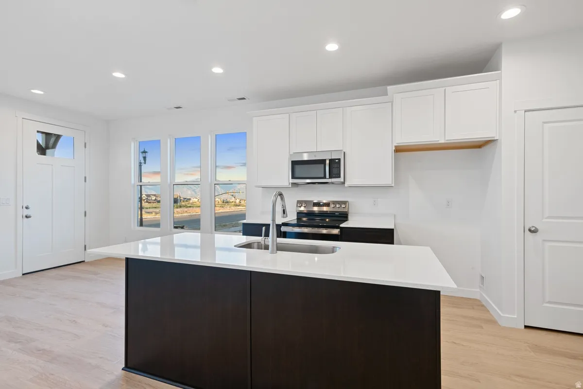 Modern kitchen island featuring a sink with a gooseneck faucet, white countertop, and dark wood-finish cabinetry