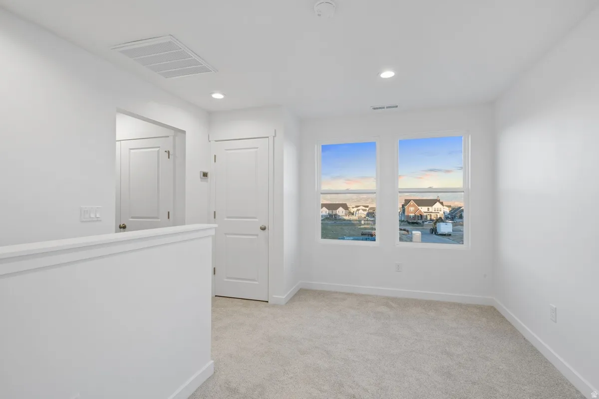 Loft space featuring two windows, recessed lighting, and light-toned carpeting