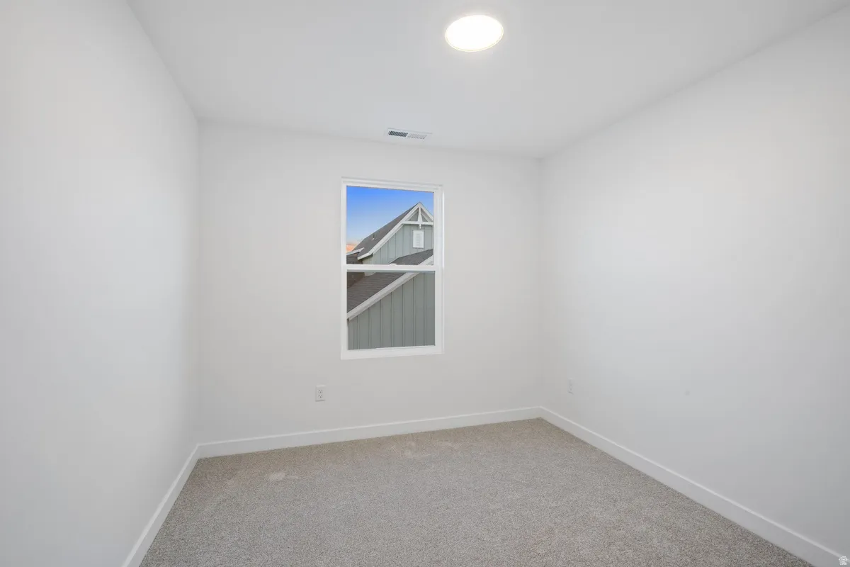 Carpeted room with a single window and recessed ceiling lighting