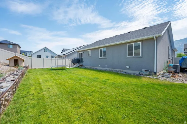 Expansive backyard featuring a manicured lawn, a privacy fence, and a decorative rock border