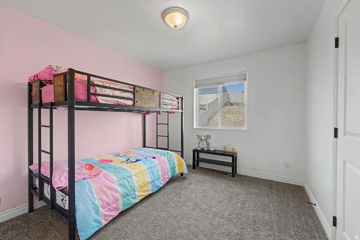 Room featuring a window with a roller shade, light gray carpeting, and a white interior door with black hardware
