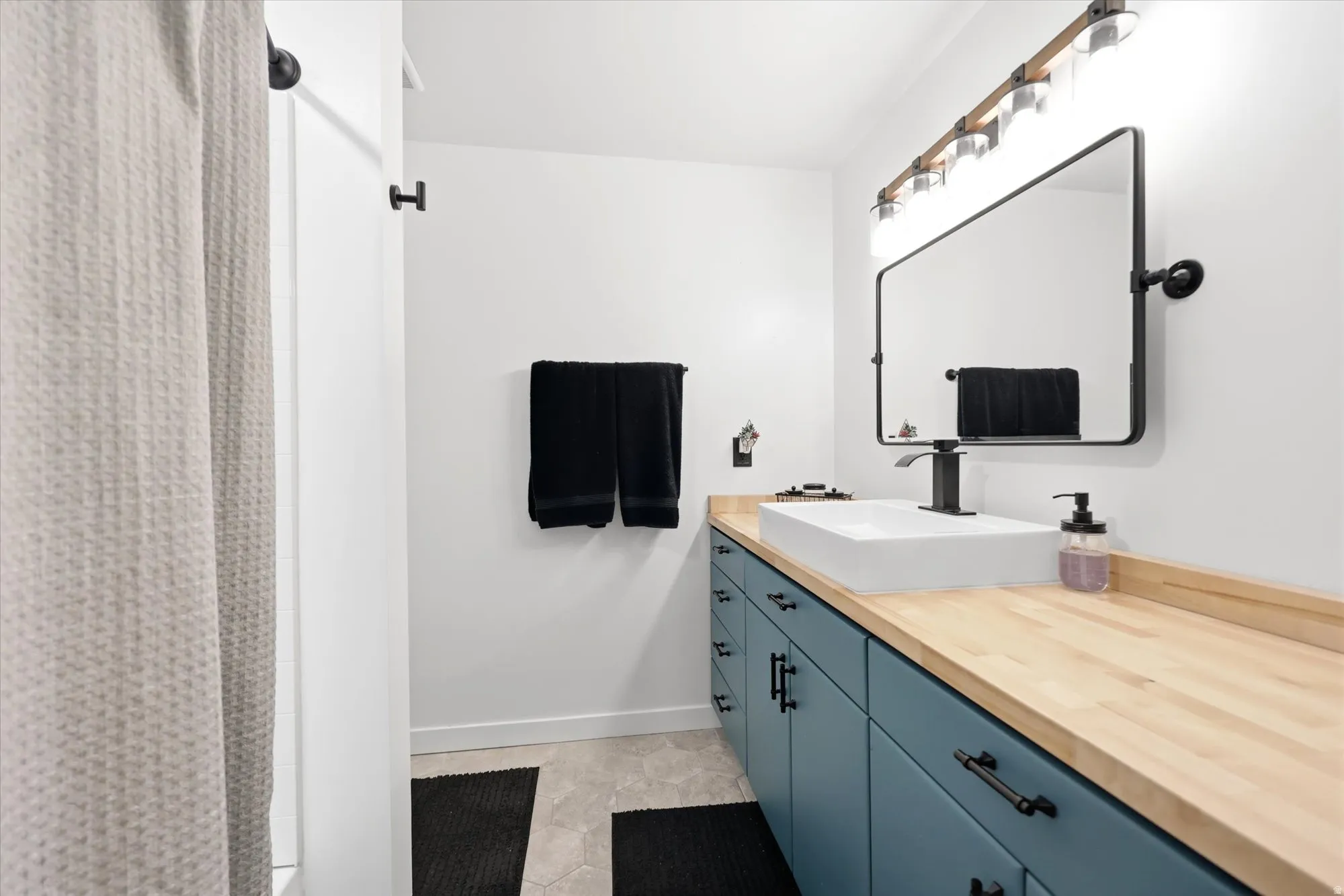 Bathroom featuring a vessel sink, wood-finish countertop, and a wall-mounted rectangular mirror