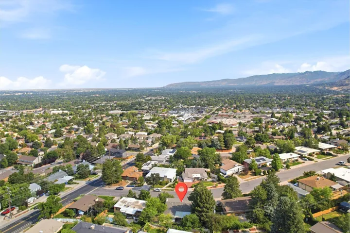 Expansive aerial view of a residential neighborhood with distant mountain backdrop, lush tree canopy, and well-established street grid