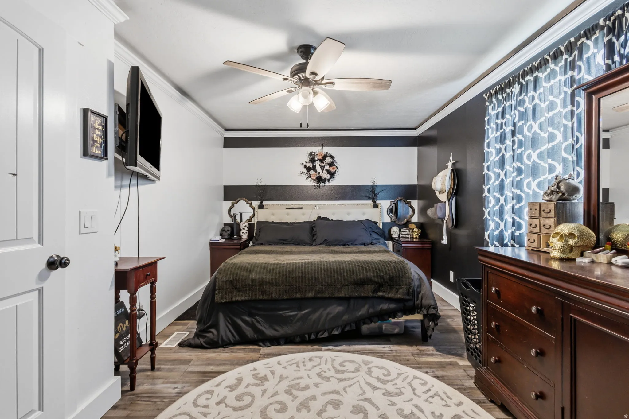 Interior room featuring wood-finish flooring, a ceiling fan, crown molding, and a paneled white door