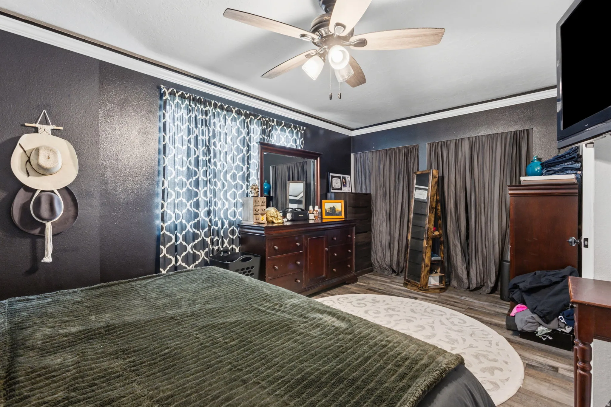 Room featuring a ceiling fan with integrated lighting, wood-finish flooring, and crown molding