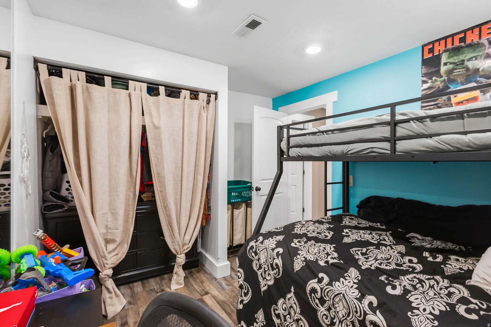 Room featuring wood-finish flooring, recessed lighting, and a closet with textile panels