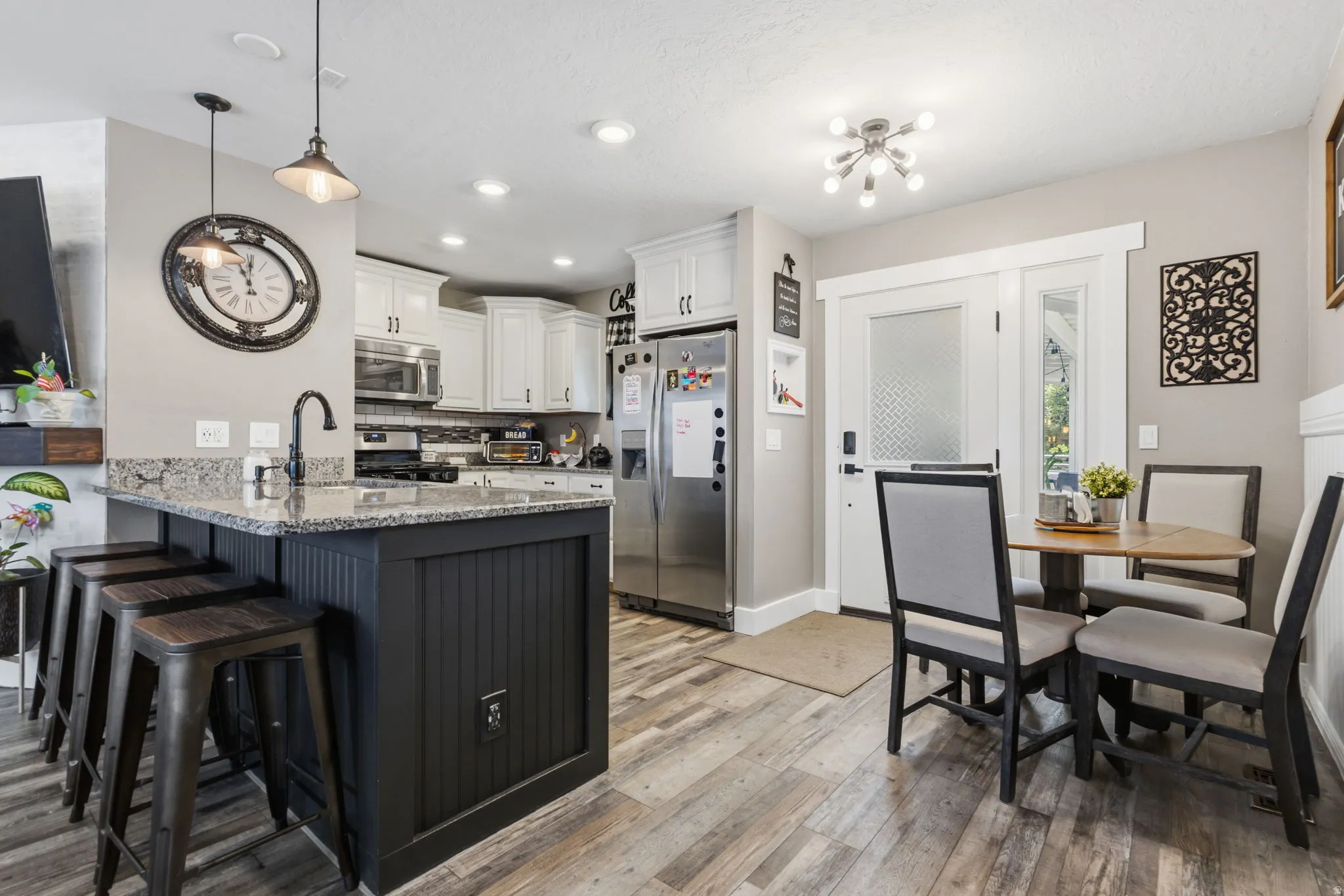 Modern kitchen featuring white cabinetry, stainless steel appliances, a center island with bar seating, and wood-finish flooring