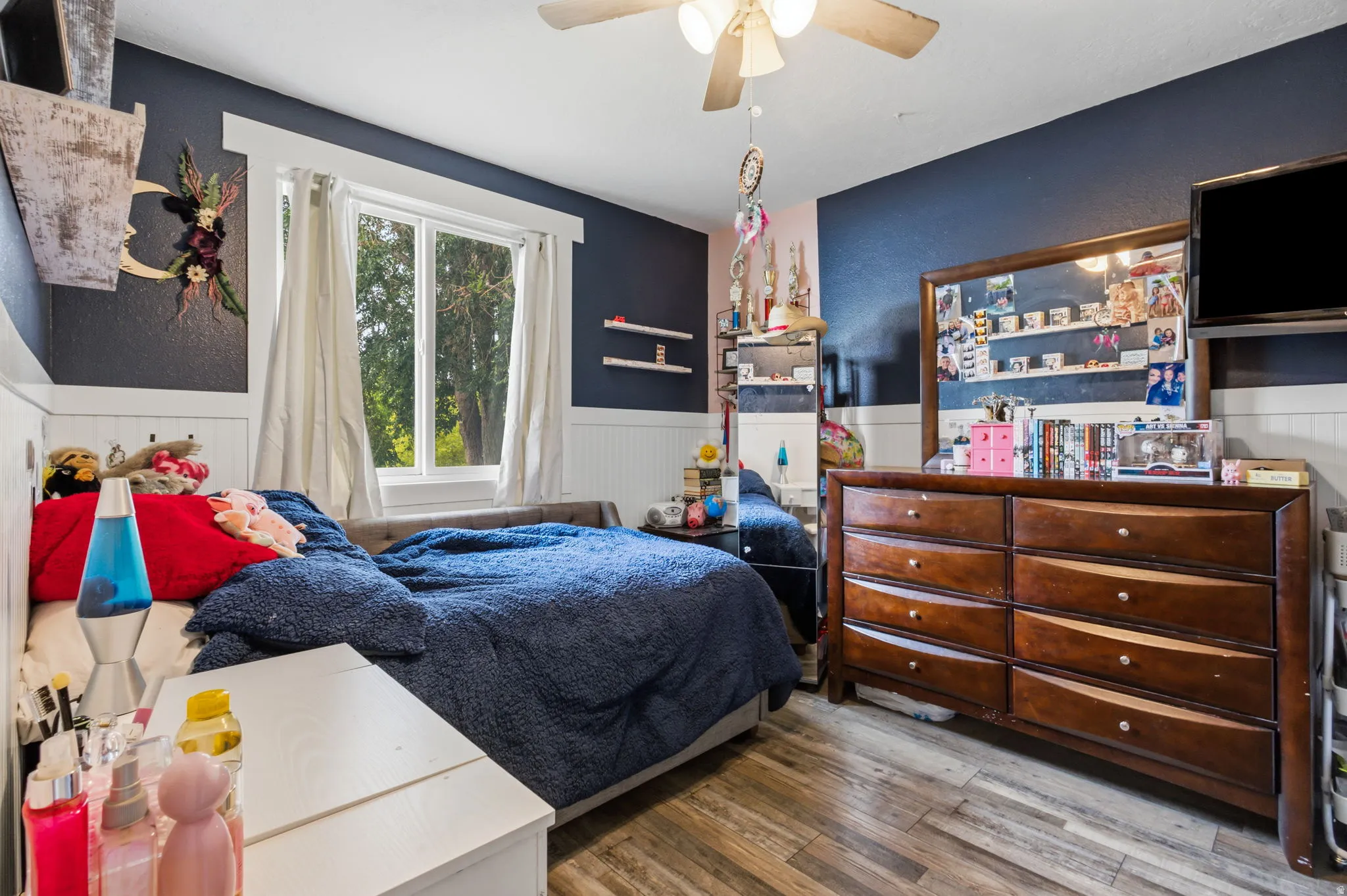 Bedroom featuring wood-finish flooring, a window with exterior views, and a ceiling fan with integrated lighting