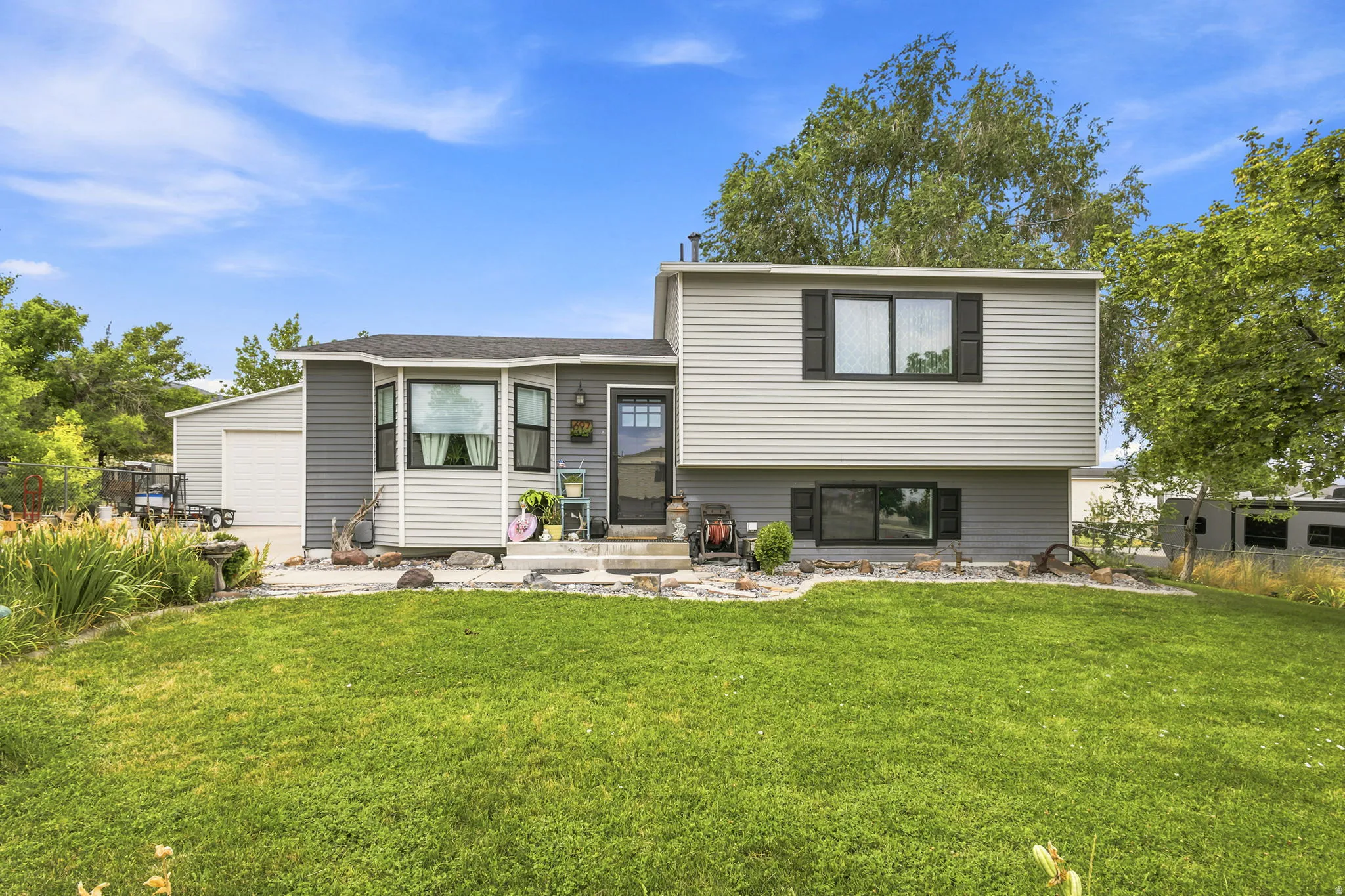 Split-level residence featuring light gray siding, a prominent bay window, and a dark entry door with decorative glass