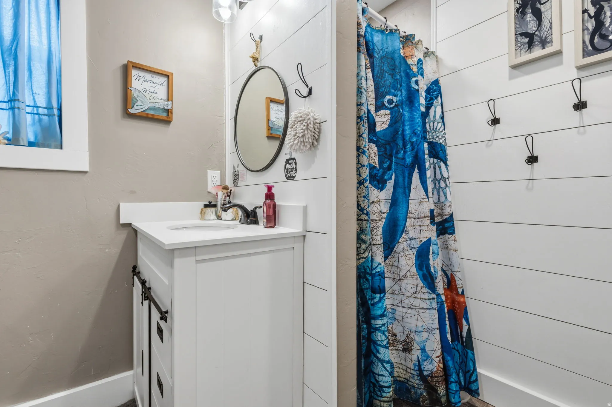 Bathroom featuring a white vanity with a single sink, black faucet, and white countertop