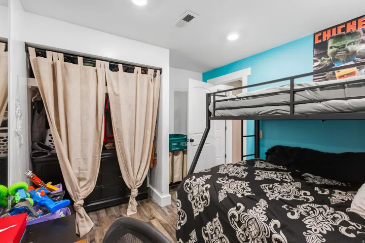 Room featuring wood-finish flooring, recessed lighting, and a closet with textile panels