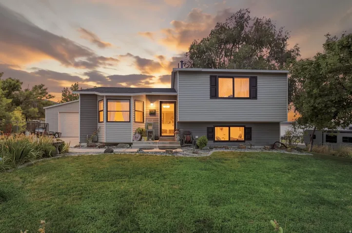 Split-level residence featuring gray horizontal siding and a dark shingle roof
