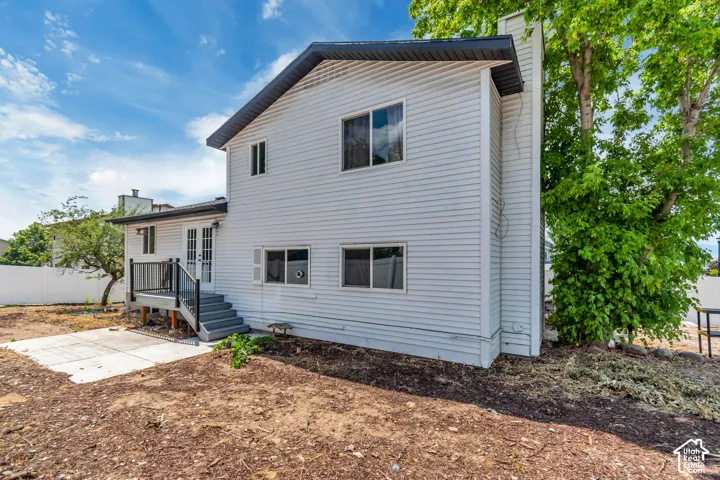 Rear exterior with small deck a concrete patio and mature trees
