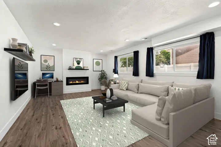 Spacious living area featuring wood-finish flooring, recessed lighting, and a modern electric fireplace with a shiplap-style surround