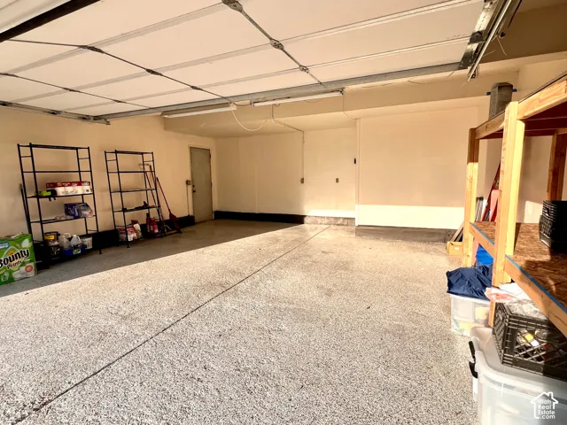 Spacious garage featuring storage, a side access door, and an epoxy-coated concrete floor