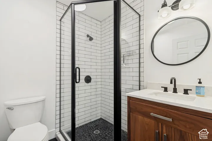 Contemporary bathroom featuring a corner glass shower with black framing, white subway tile walls, and a dark pebble-finish floor