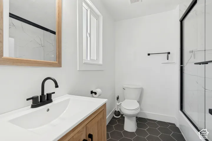 Bathroom featuring a natural wood-finish vanity, white countertop with integrated sink, matte black faucet, and a framed mirror