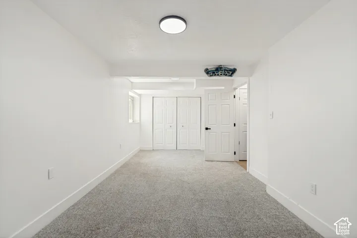Spacious room featuring light gray carpet, crisp white walls, and a recessed window