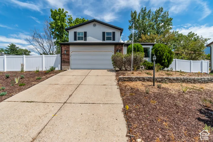 Two-story residence featuring siding and brick accents, an attached garage, and a concrete driveway
