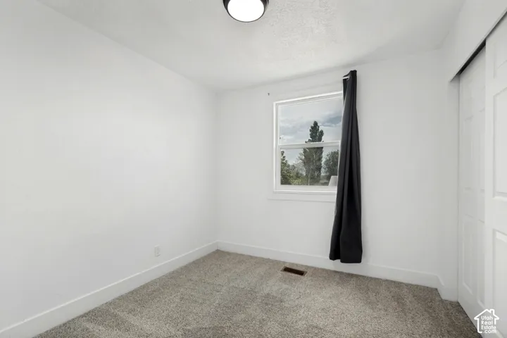 Room featuring light gray carpet, white walls, and a single window with white trim