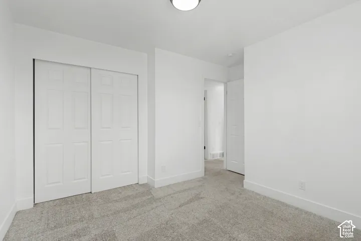 Room featuring neutral carpeting, white baseboards, and a flush mount ceiling light