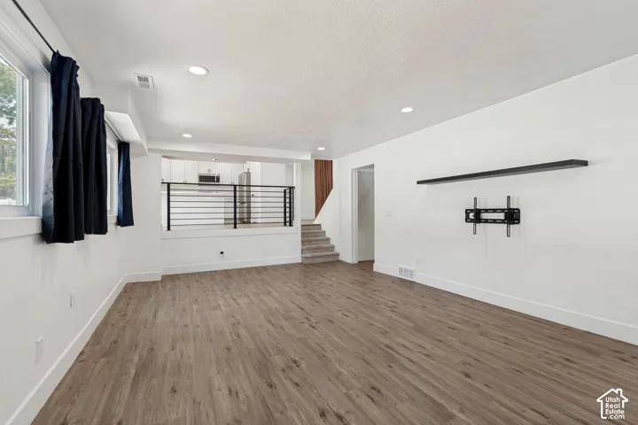 Spacious living area featuring wood-finish flooring, recessed lighting, and white walls