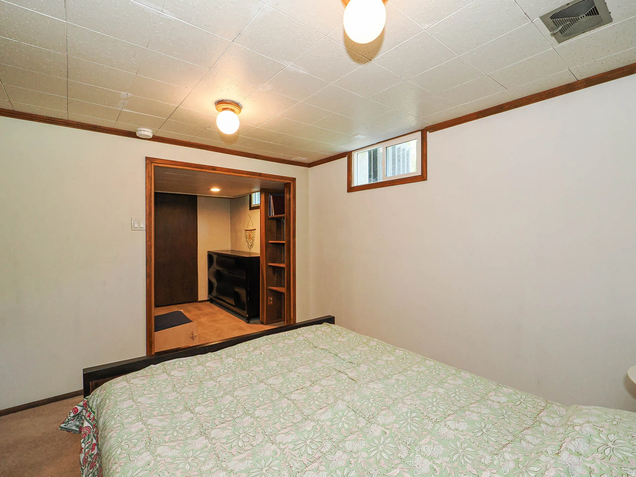 Room featuring a drop ceiling, wood-finish trim, and wall-to-wall carpeting