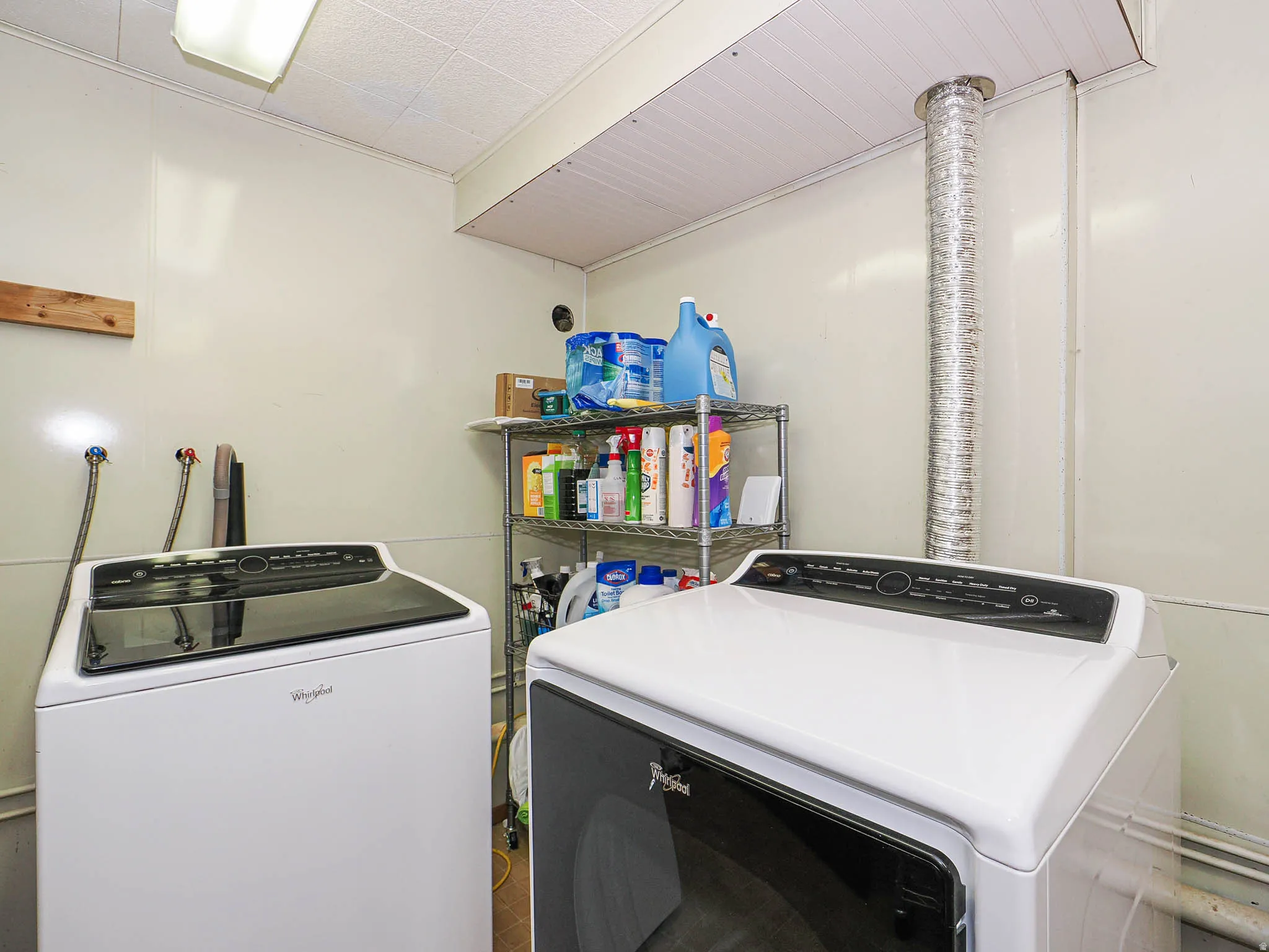 Dedicated laundry area featuring a washer and dryer, white paneling, and a fluorescent ceiling light