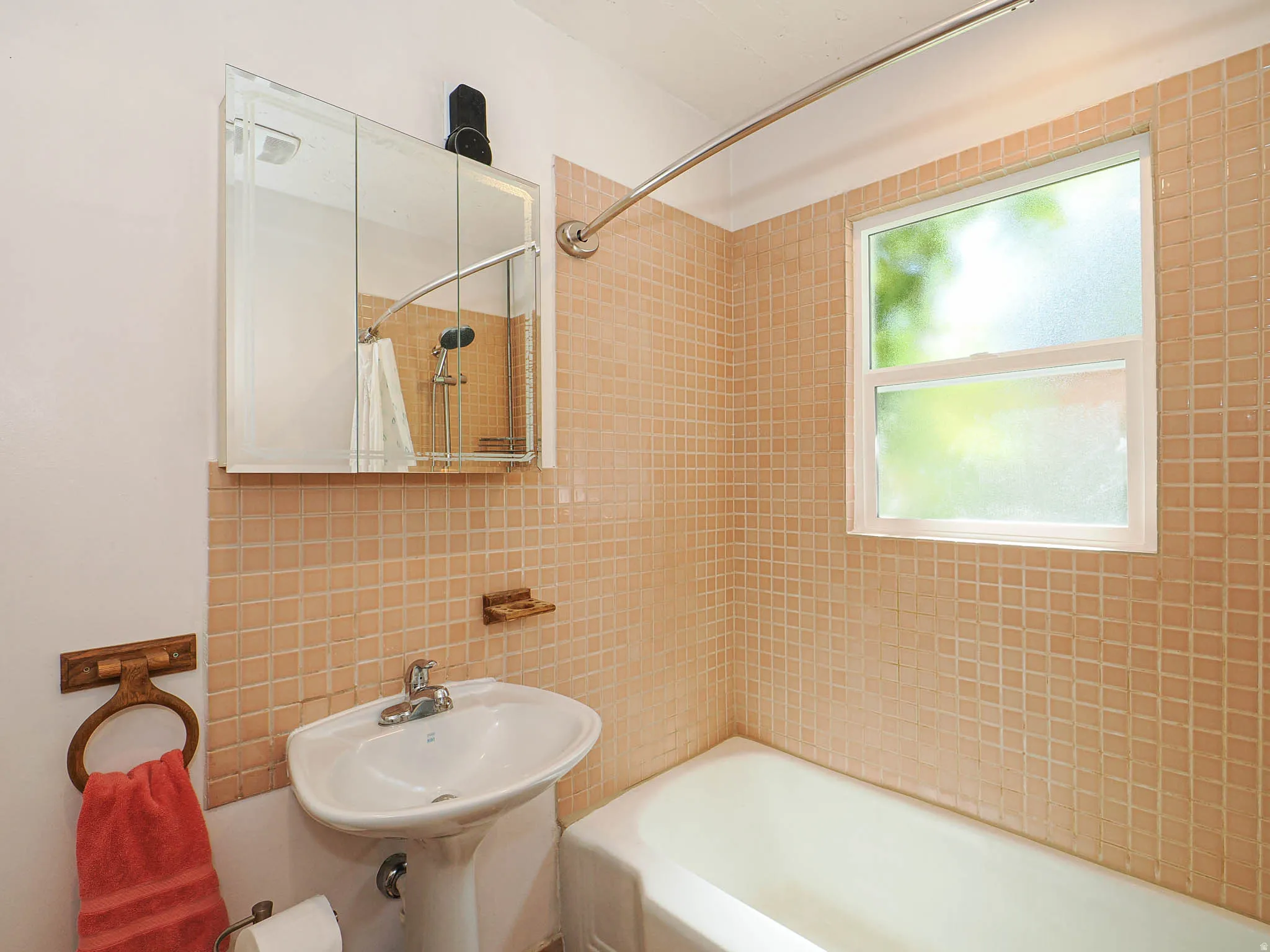 Pedestal sink with chrome faucet, complemented by a mirrored medicine cabinet