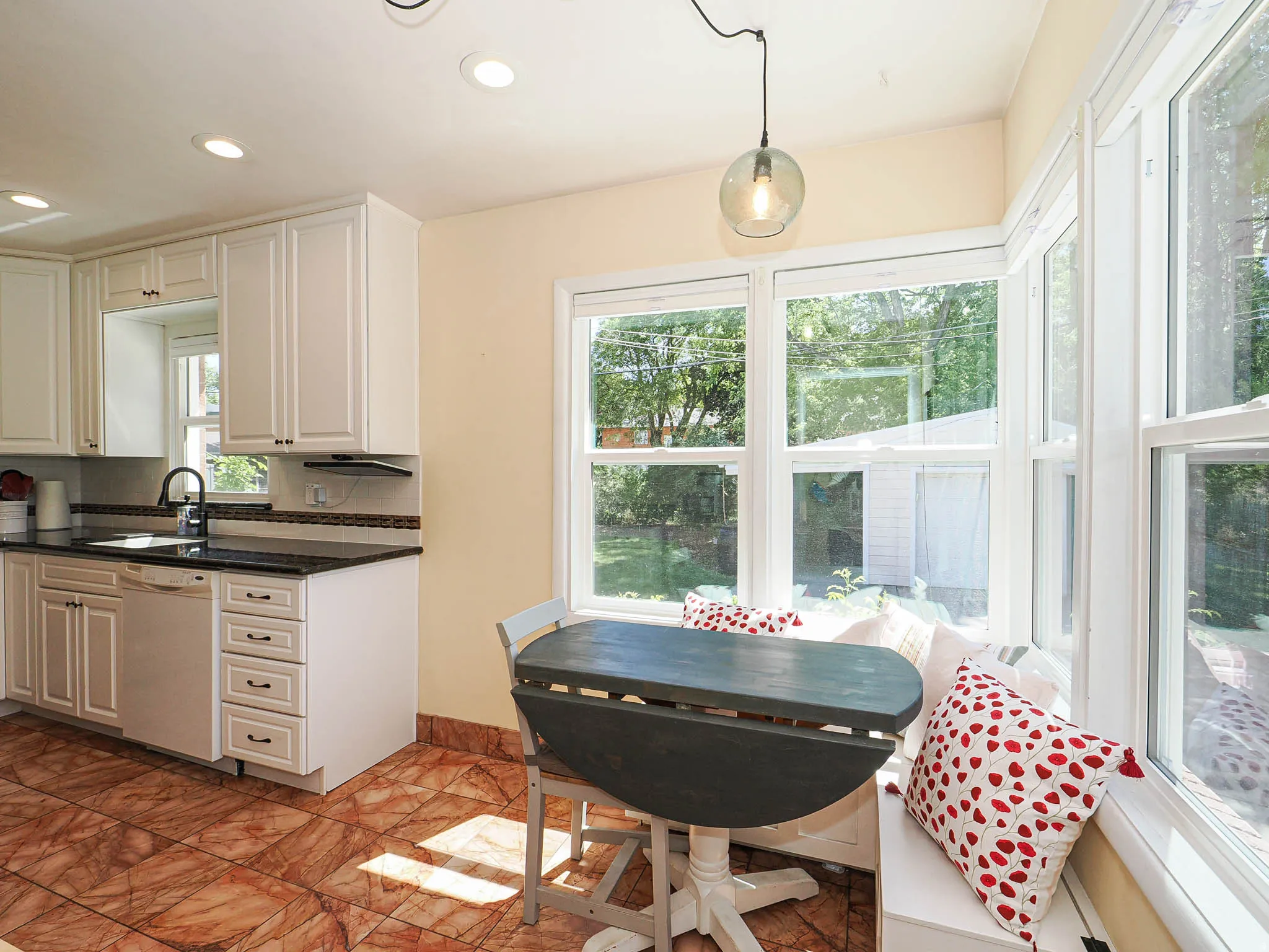 Kitchen featuring white cabinetry, dark countertops, a built-in dishwasher, and a black faucet