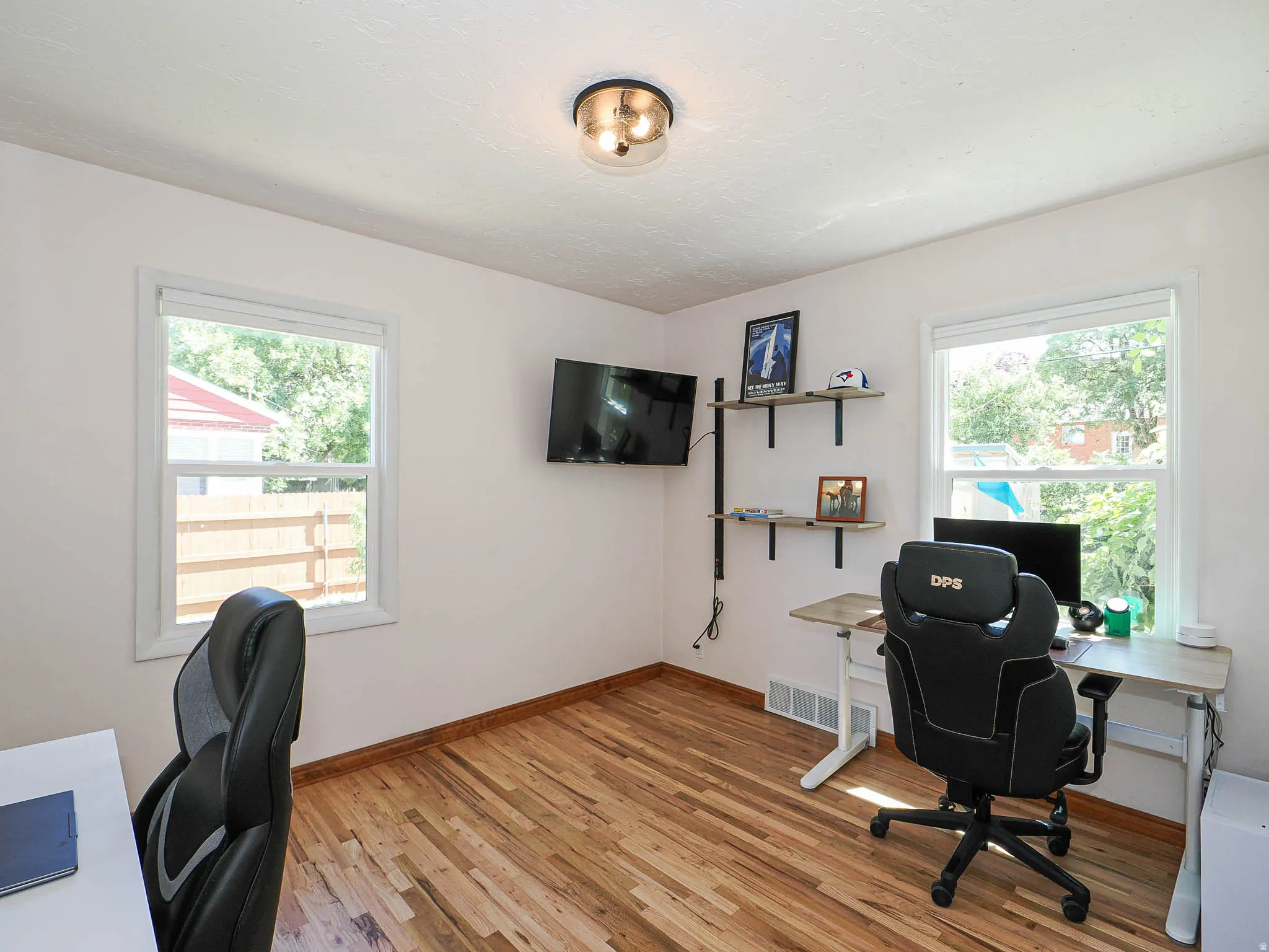 Room featuring wood-finish flooring and two windows providing natural illumination