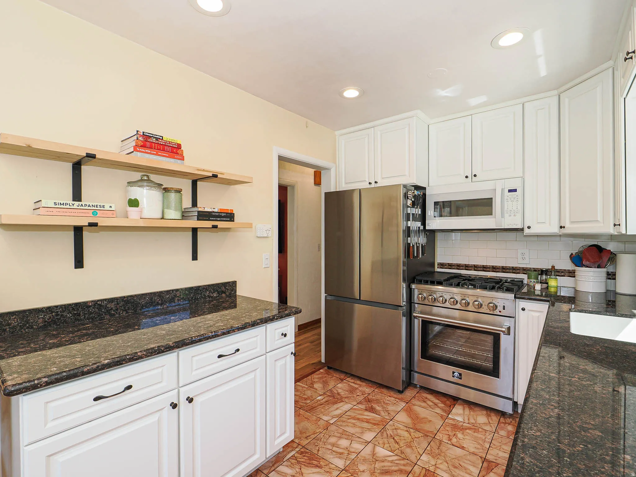 Kitchen featuring white cabinetry, dark granite countertops, stainless steel appliances, and tiled flooring
