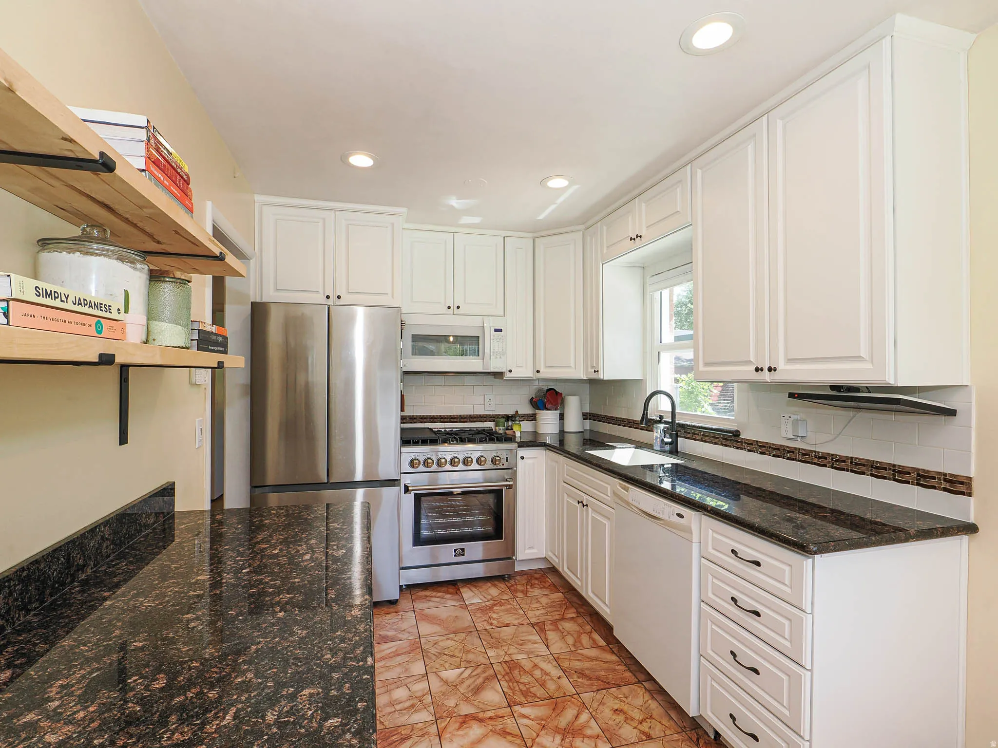 Kitchen featuring white cabinetry, dark stone countertops, stainless steel appliances, and a tiled floor