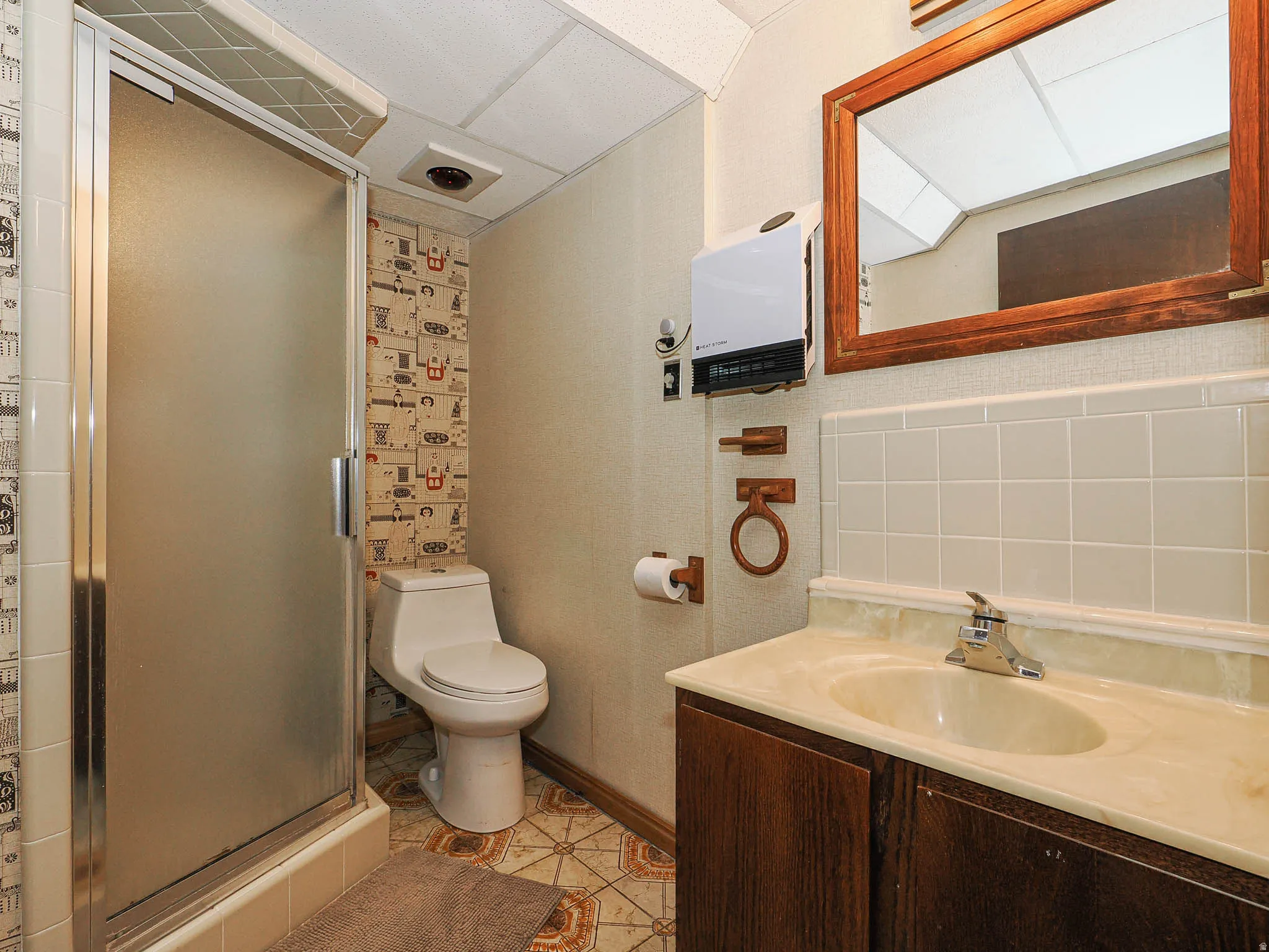 Bathroom featuring a standing shower with frosted glass enclosure, a white commode, and a vanity with an integrated sink