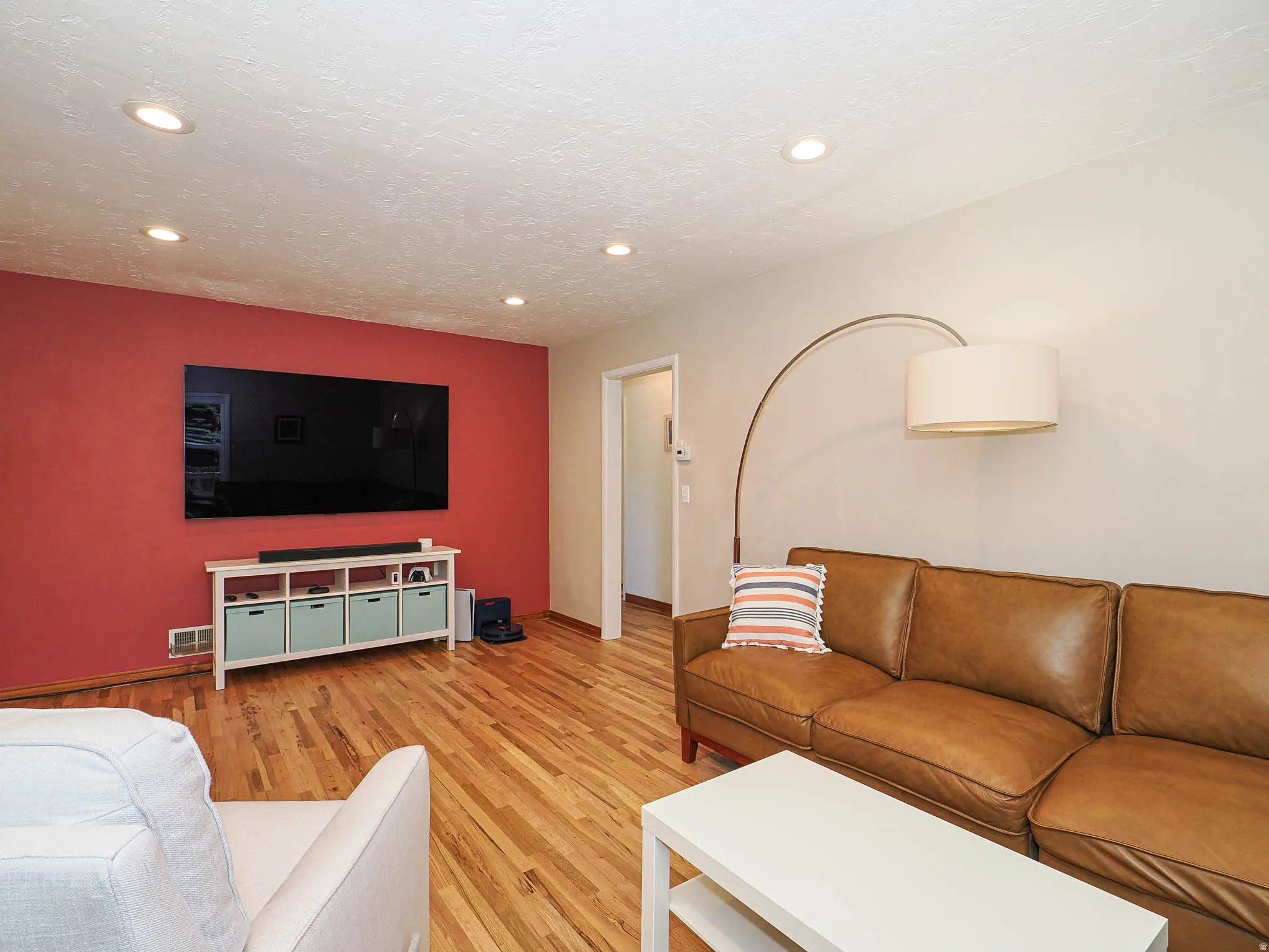 Living area featuring wood-finish flooring, recessed ceiling lighting, and a red accent wall