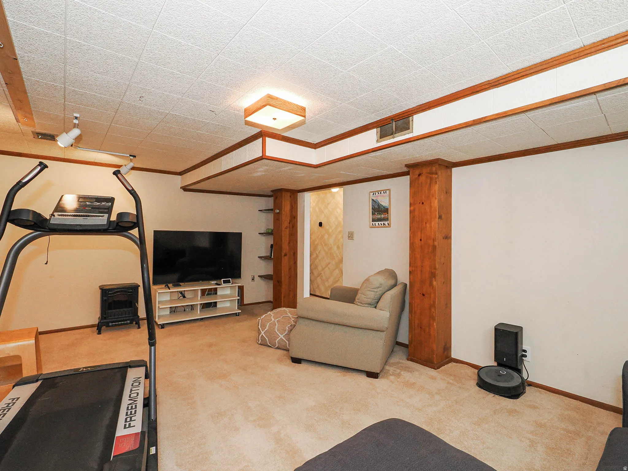 Carpeted room with a drop ceiling and wood trim accents